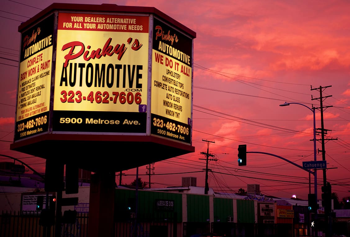 Pinky's Automotive Hollywood signage glowing at sunset over Melrose Avenue